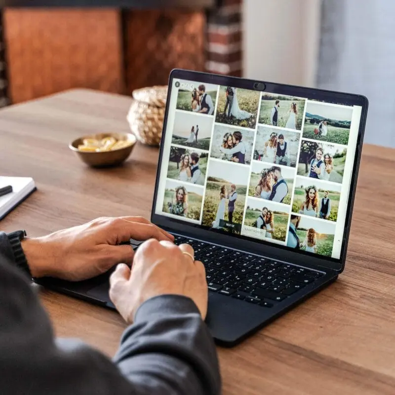 Ein Fotograf, der auf seinen Laptop-Bildschirm schaut, auf die Fotos und Videos in der erstellten Galerie. Ein letzter Check, vor der Lieferung an die Kunden.